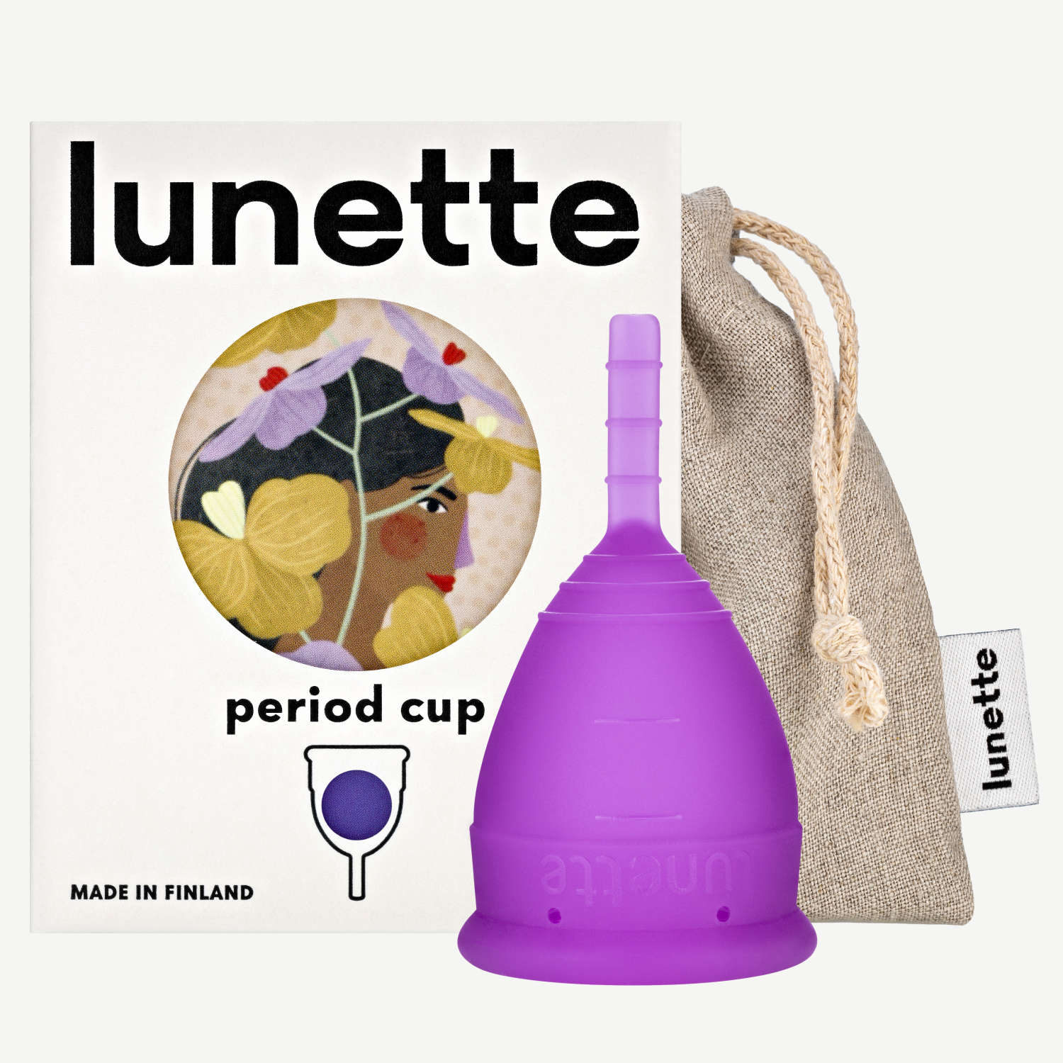 A purple Lunette period cup displayed alongside its packaging box with a floral design and a linen storage pouch. The box includes the text 'period cup', 'made in Finland', and the brand name 'Lunette'.